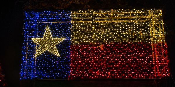 Texas flag created with blue, yellow, and red lights at night.
