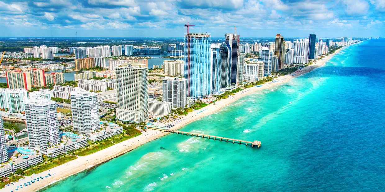 Aerial view of a beach city with turquoise waters and high-rise buildings.