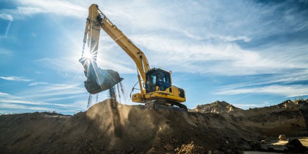 Excavator digging dirt under bright sun.