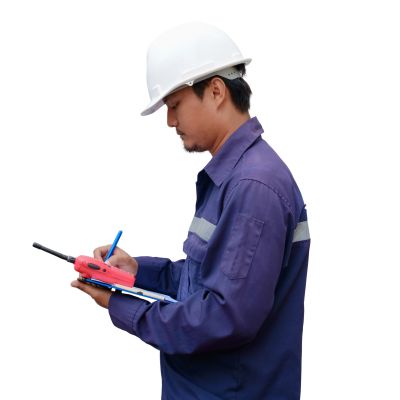Engineer in safety helmet writing on clipboard.