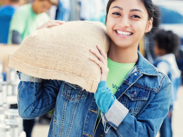 Smiling young woman carrying a sack on her shoulder.