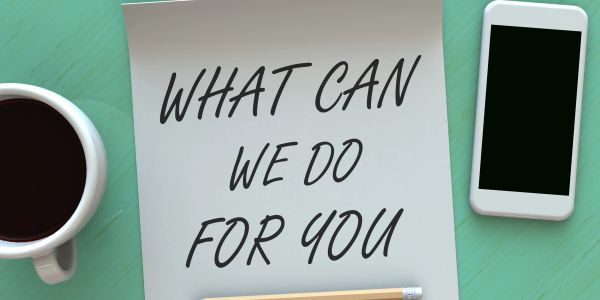 Note asking "What can we do for you" on a desk with coffee and phone.
