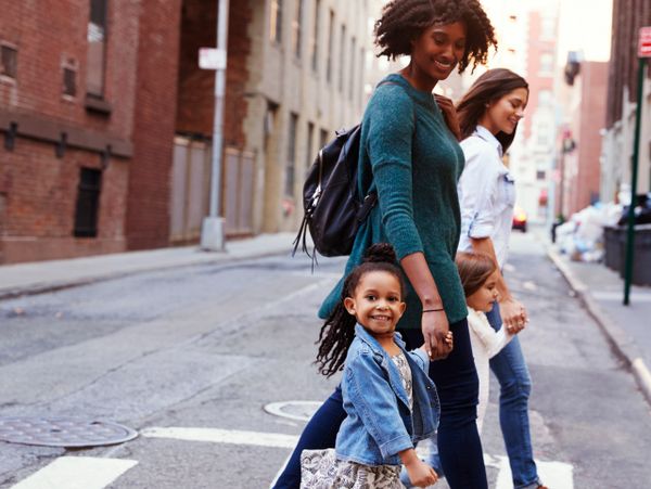 Two women and two children happily crossing a city street together.