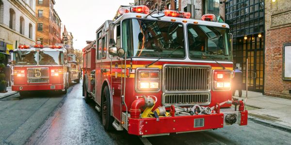 Two red fire trucks parked on a city street.