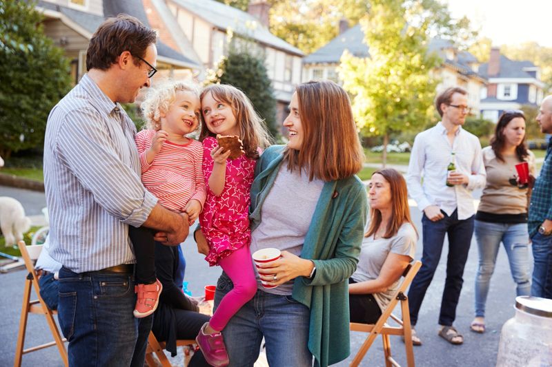 Parents holding their young kids while they eat at a block party