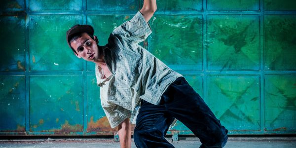 Man breakdancing in front of a green wall.