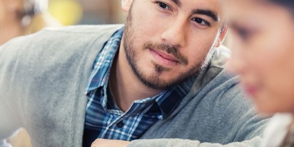 Man attentively listening to a blurred woman in a casual setting.