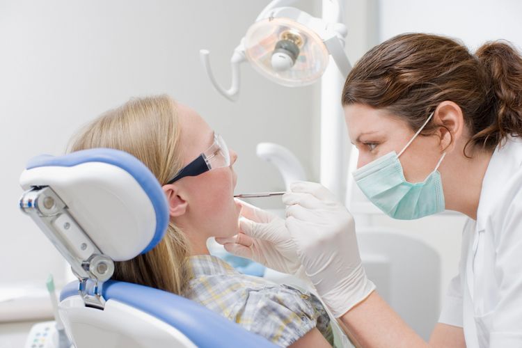 Dentist examining a young patient's teeth in a dental clinic.