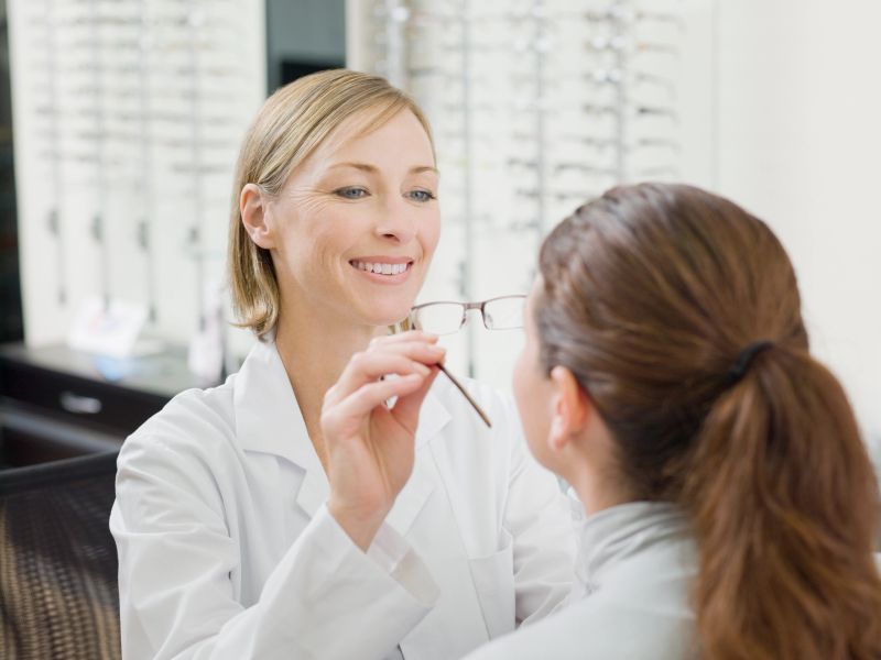 Woman trying on glasses in optometrists shop