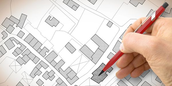 a residential street showing houses with a hand and a pencil to mark up the map for town plans