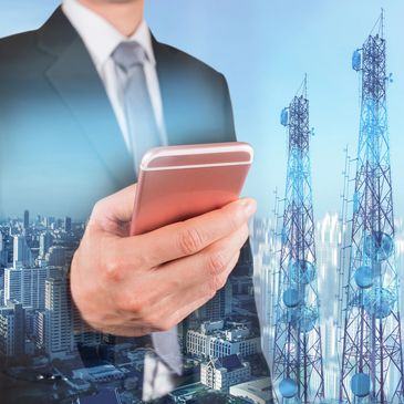 Businessman using smartphone with telecommunications towers and cityscape background.