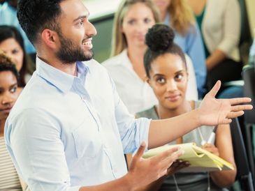 Man presenting confidently to an attentive audience in a seminar.