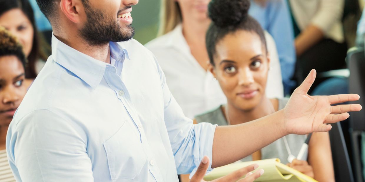 Man speaking to an attentive audience in a seminar or meeting.