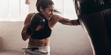 Woman training with boxing gloves on a punching bag.