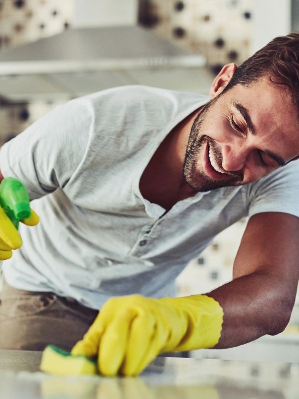 Man cleaning a counter with a big smile on his face