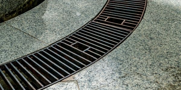 Curved metal grate on a stone pavement.