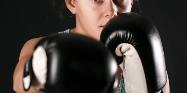 Focused woman in boxing gloves throwing a punch toward the camera.