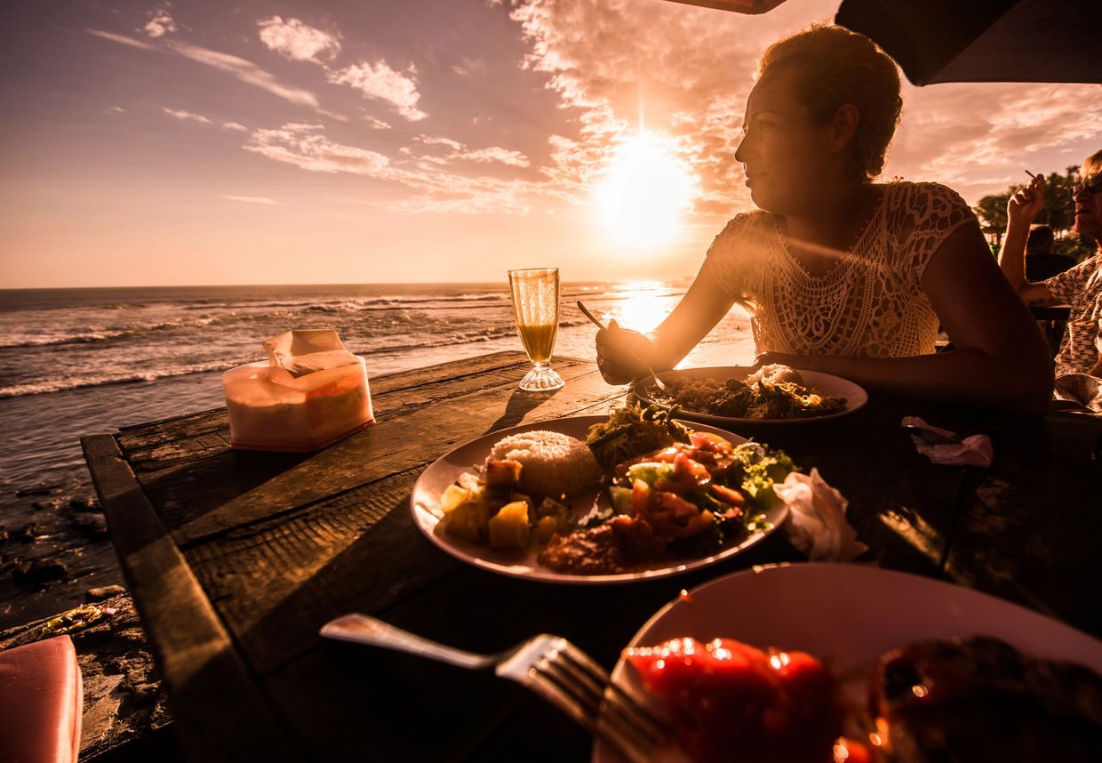 A Mentawai Surfer eating a meal on the beach at sunset.