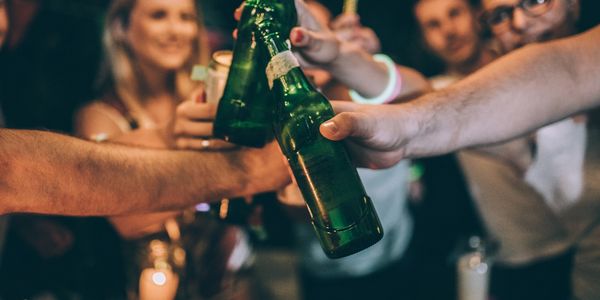 Friends clinking green beer bottles in a celebratory toast.