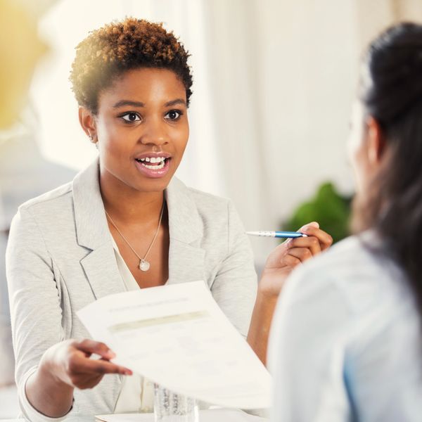 Businesswoman discussing documents with colleague in an office.