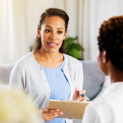 A woman attentively listening and taking notes during a conversation.