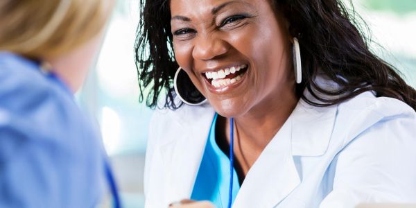 Smiling healthcare professional in a white coat interacting with a patient.