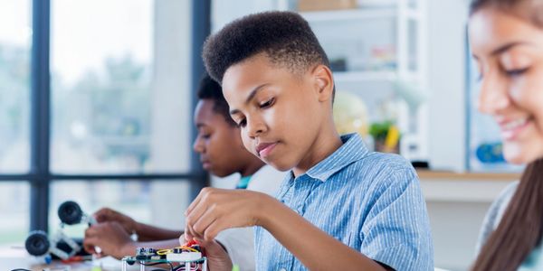 Children engaged in building and programming robots in a classroom.