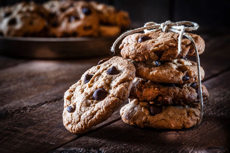 Chocolate chip cookies close up shot on rustic wooden table. Four cookies are arranged in a stack and tied up with a rustic string and the fifth one is supported from the stack. The composition is at the right of the frame leaving useful copy space for text and/or logo at the left. Low key DSRL studio photo taken with Canon EOS 5D Mk II and Canon EF 100mm f/2.8L Macro IS USM