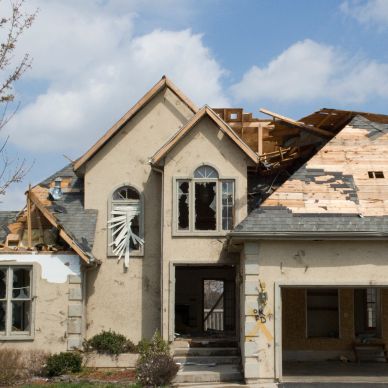 Damaged house with broken windows and roof.