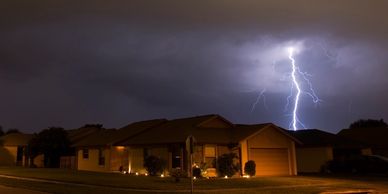 Lightning striking near a house at night.