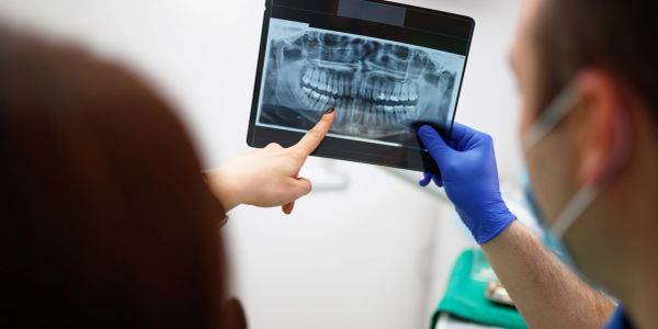 Doctor holding a panoramic dental xray and the patient pointing at her teeth