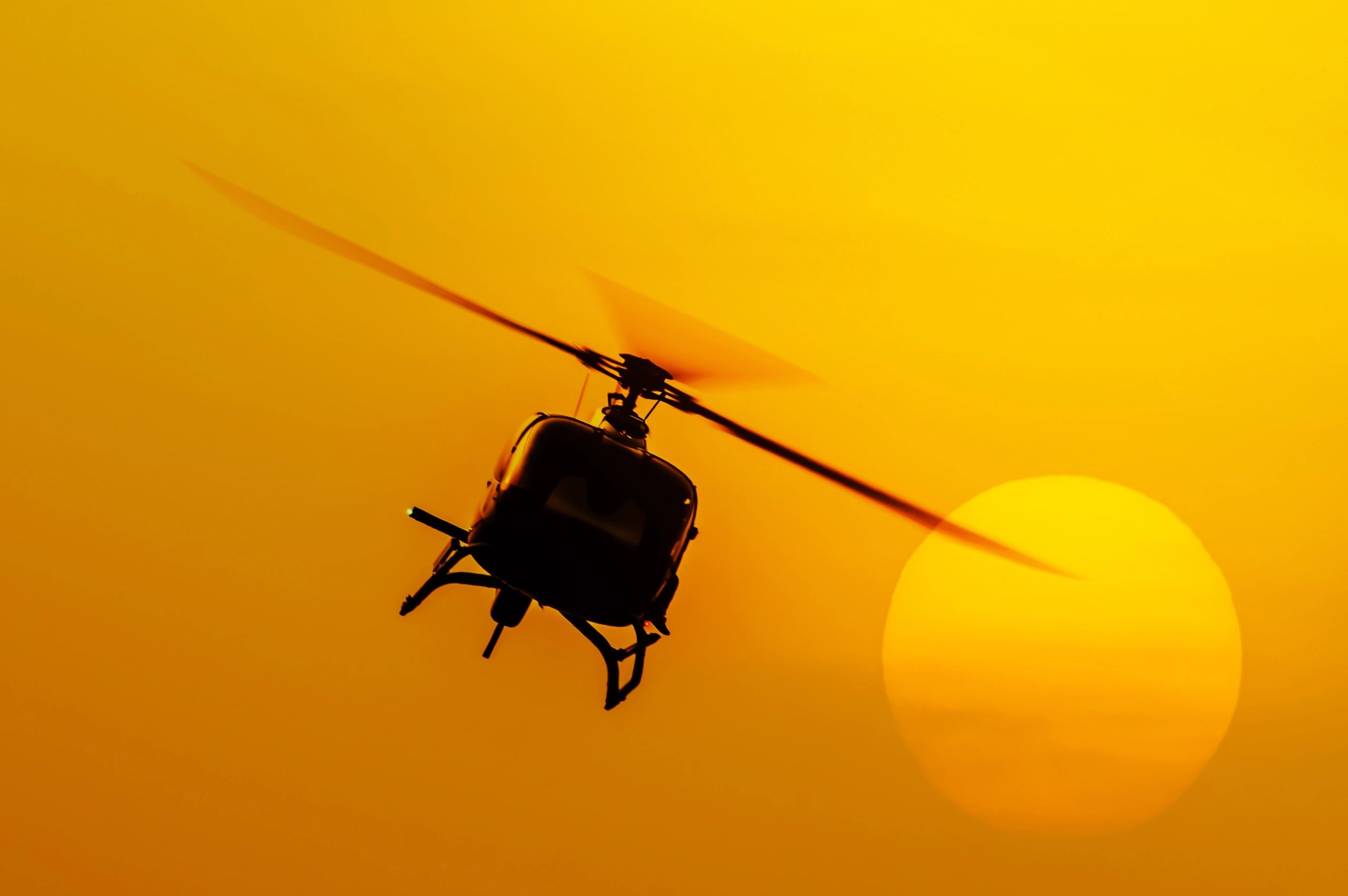 Helicopter flying against a vibrant sunset.