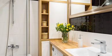 Modern bathroom with wooden accents and a compact washing machine.