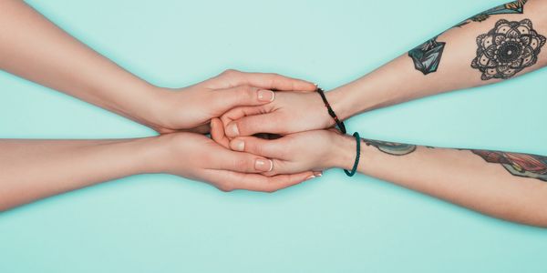 Two sets of arms and hands. One set cupping the other in a comforting way. 