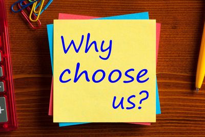 Sticky notes with 'Why choose us?' written on top of a wooden desk.