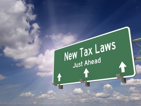 Highway sign warning of new tax laws ahead under a sunny sky.
