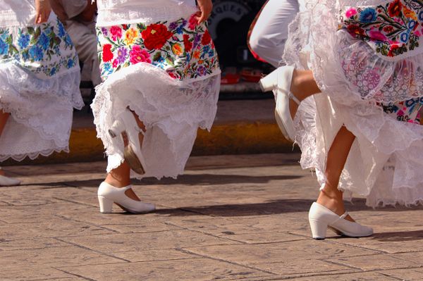 Women dancing in traditional embroidered dresses and white shoes.