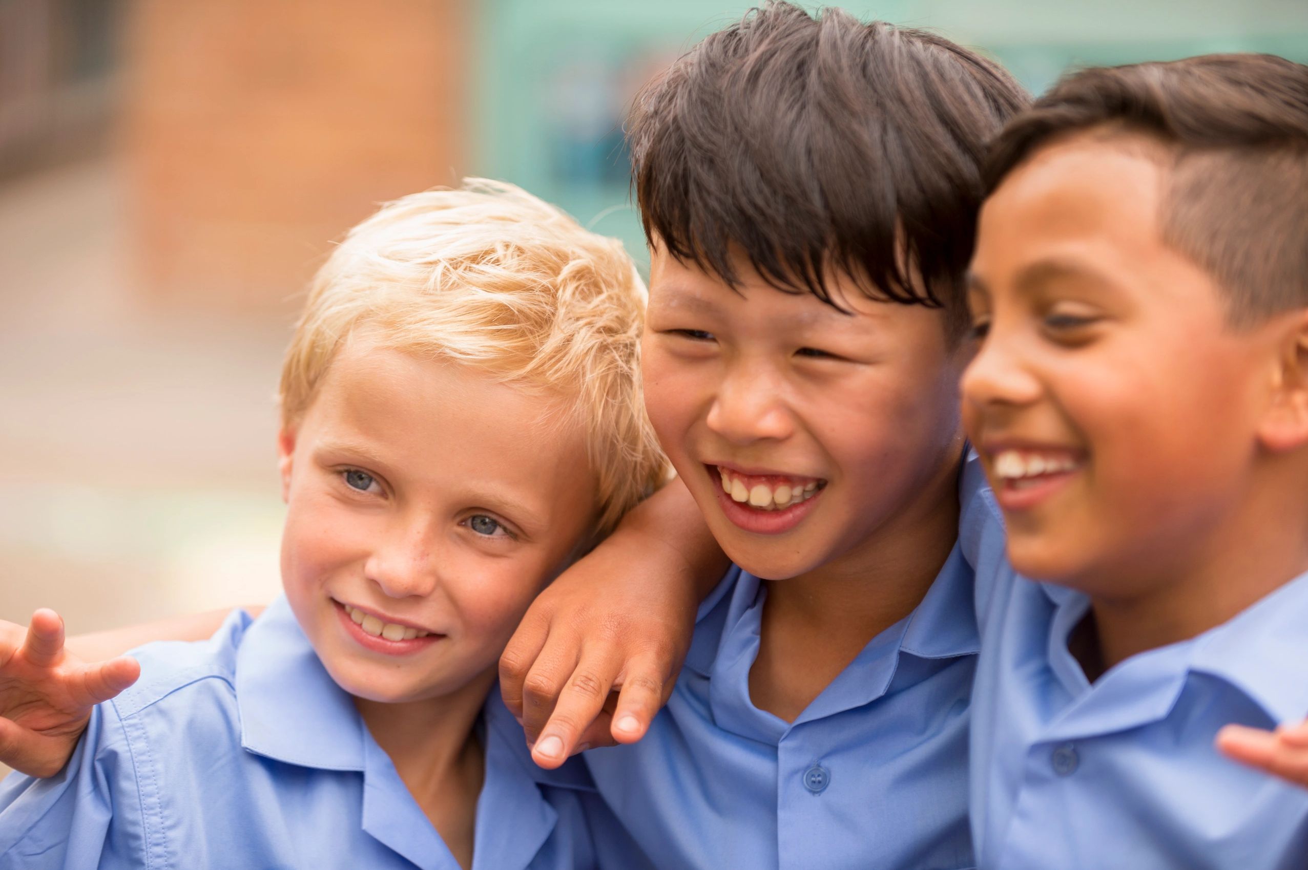Three boys happily posing together in school uniforms.