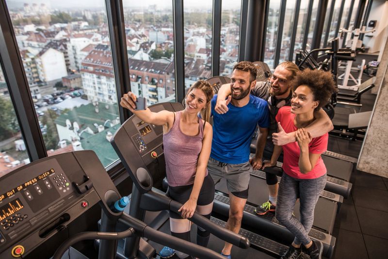 High angle view of group of happy athletes having fun in a gym while taking a selfie with mobile phone.