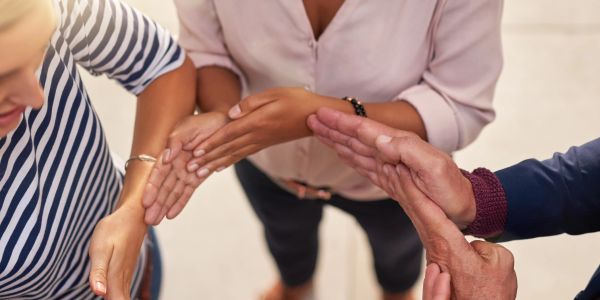 Group of people stacking hands in a team gesture.