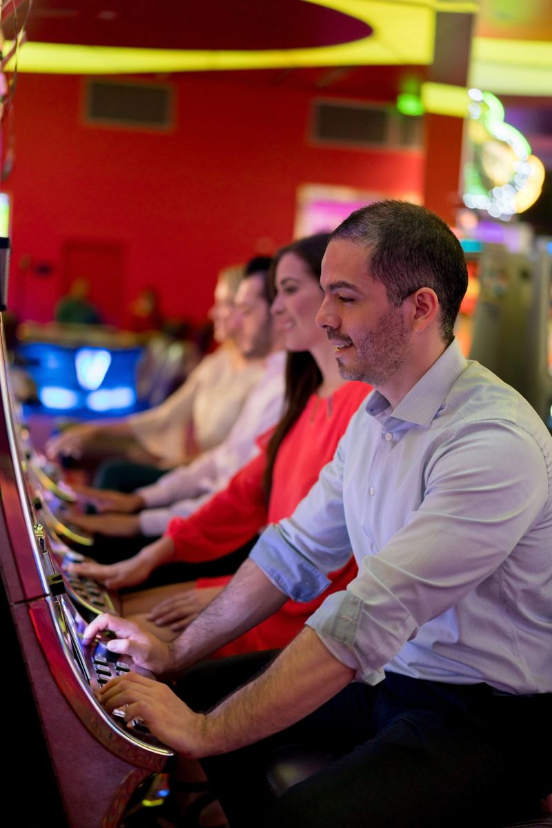 Happy group of people playing at the casino on the slot machines and smiling - lifestyle concepts