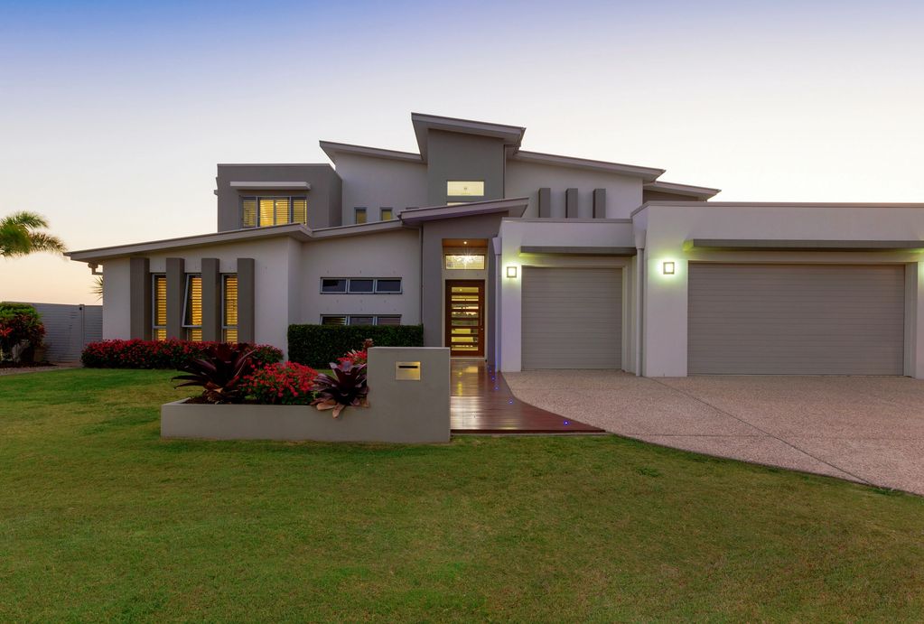 Modern house with sleek architecture and well-maintained lawn at dusk.