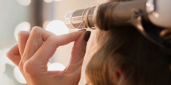 Close-up of a woman curling her hair with a curling iron.