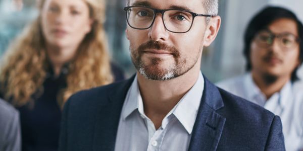 Confident businessman with colleagues blurred in the background.