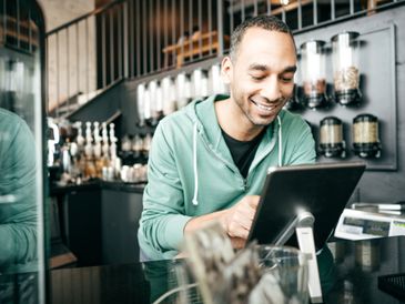 Smiling man using a tablet in a cozy café setting.