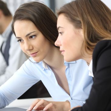 Two women collaborating and discussing work on a laptop.