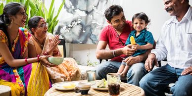 A joyful family spending time together, laughing and sharing food indoors.