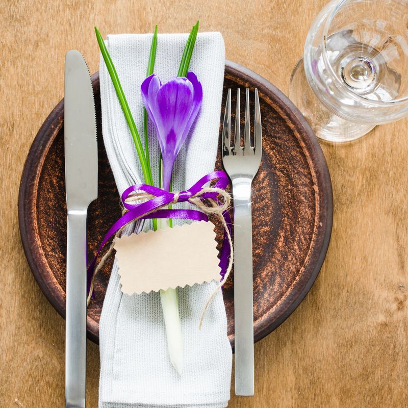 Spring Festive Table Setting With Fresh Flower and Empty Card. Napkin, plate and cutlery on wooden table. Holidays background. Selective Focus.