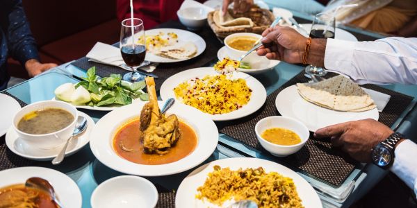 People enjoying a meal with Indian dishes on a table.