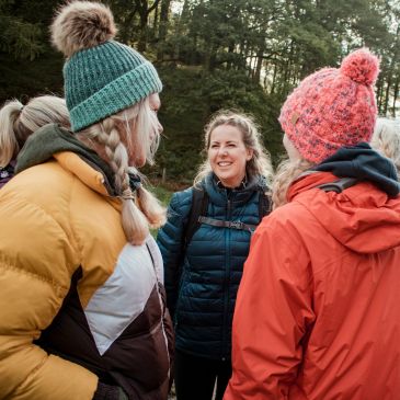 Three women in winter clothes chatting outdoors.